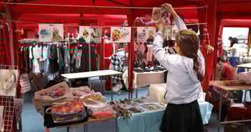 woman displaying clothes for sale in a booth outside