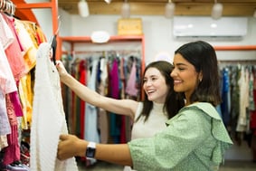 two women looking at clothing in thrift store