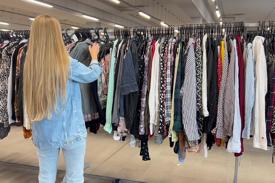 A woman browsing a clothing rack at a thrift store.