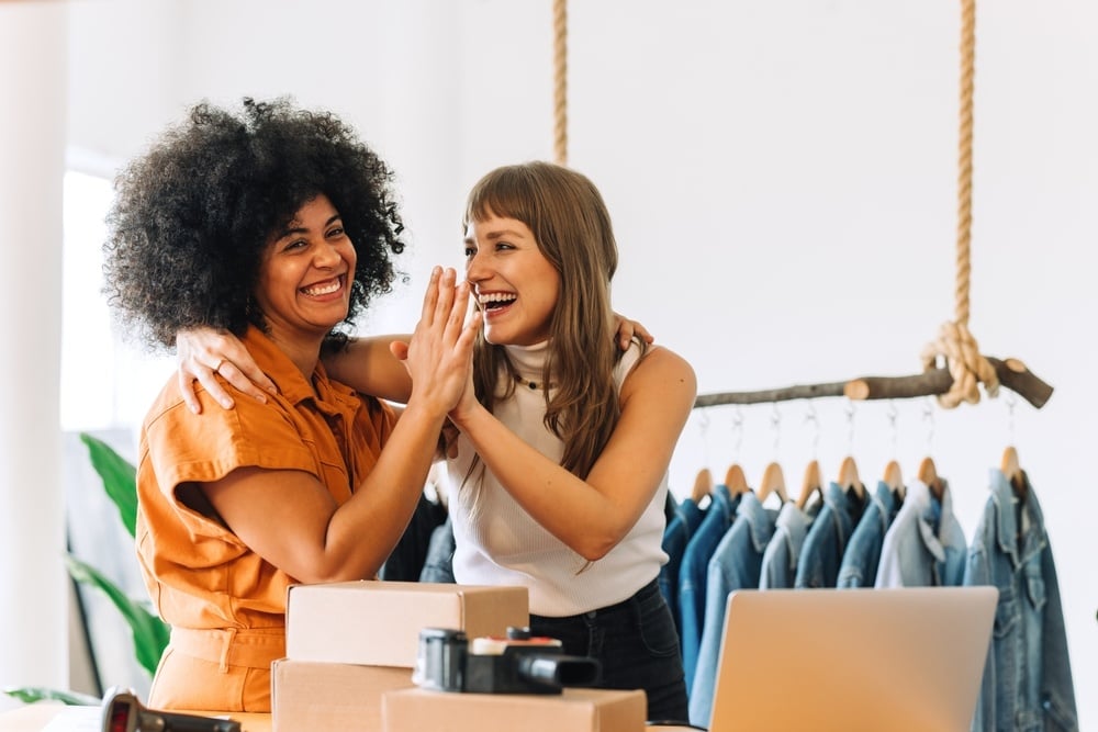 two women high fiving and smiling in thrift store