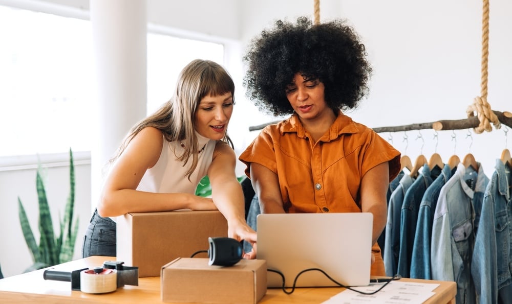 two female employees in a thrift store looking at a computer