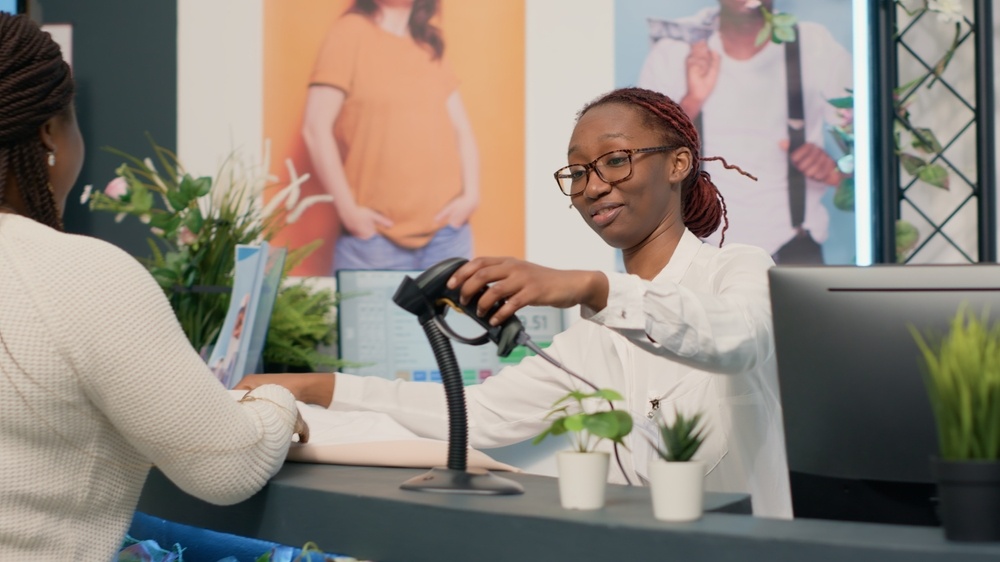 African american shopkeeper processing items in thrift shop at checkout counter for customers waiting in line. Close up shot of employee assisting woman with her purchases in second hand store